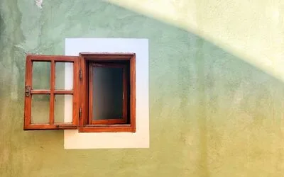 An open brown wooden window on a stucco wall