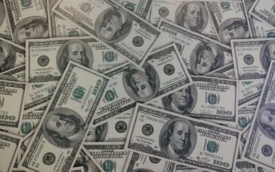 Scattered United States one hundred dollar bills covering a flat surface